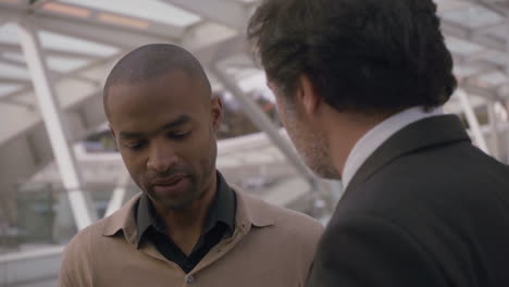 african american man talking to colleague near office building