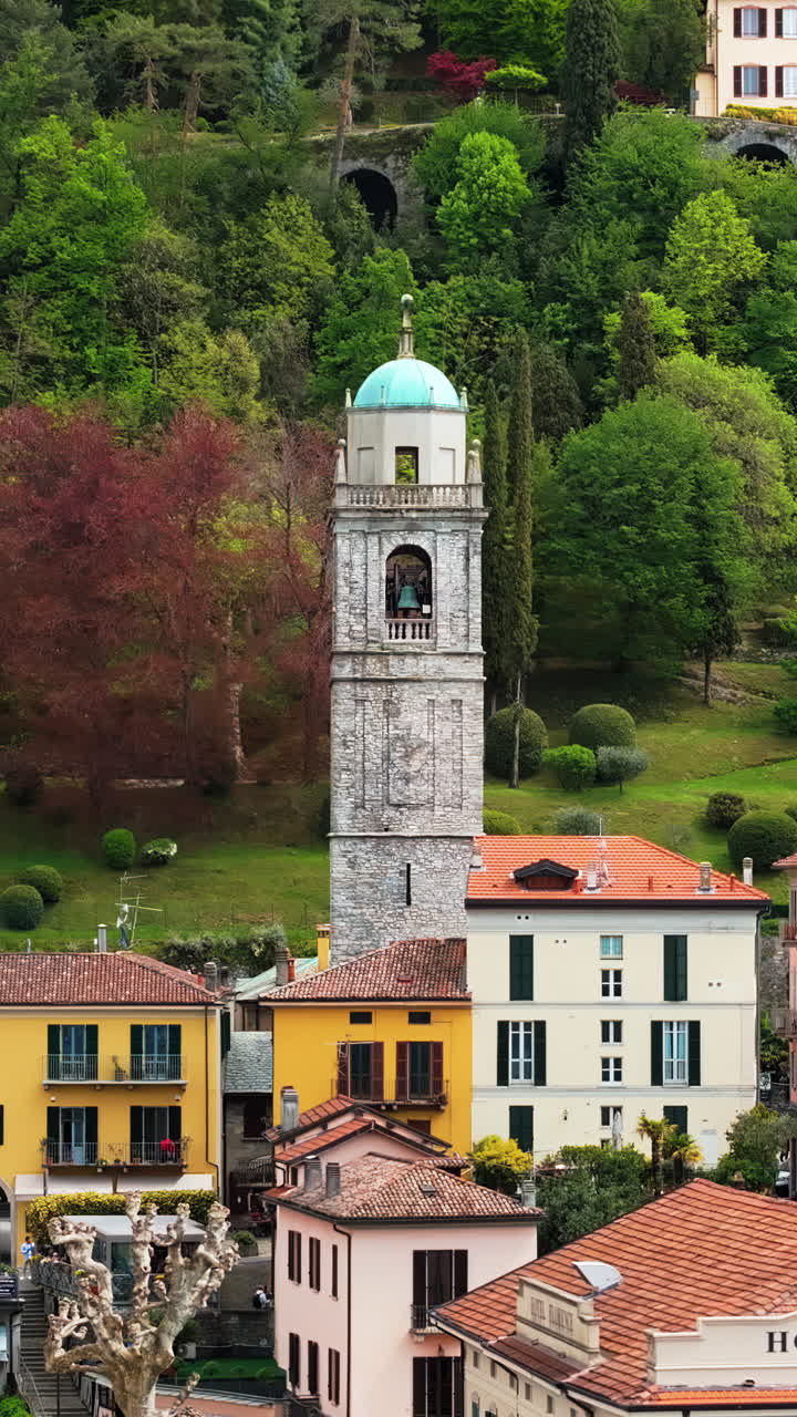 Aerial drone view of the Basilica of St. Giacomo surrounded by houses in Bellagio, Italy. Vertical