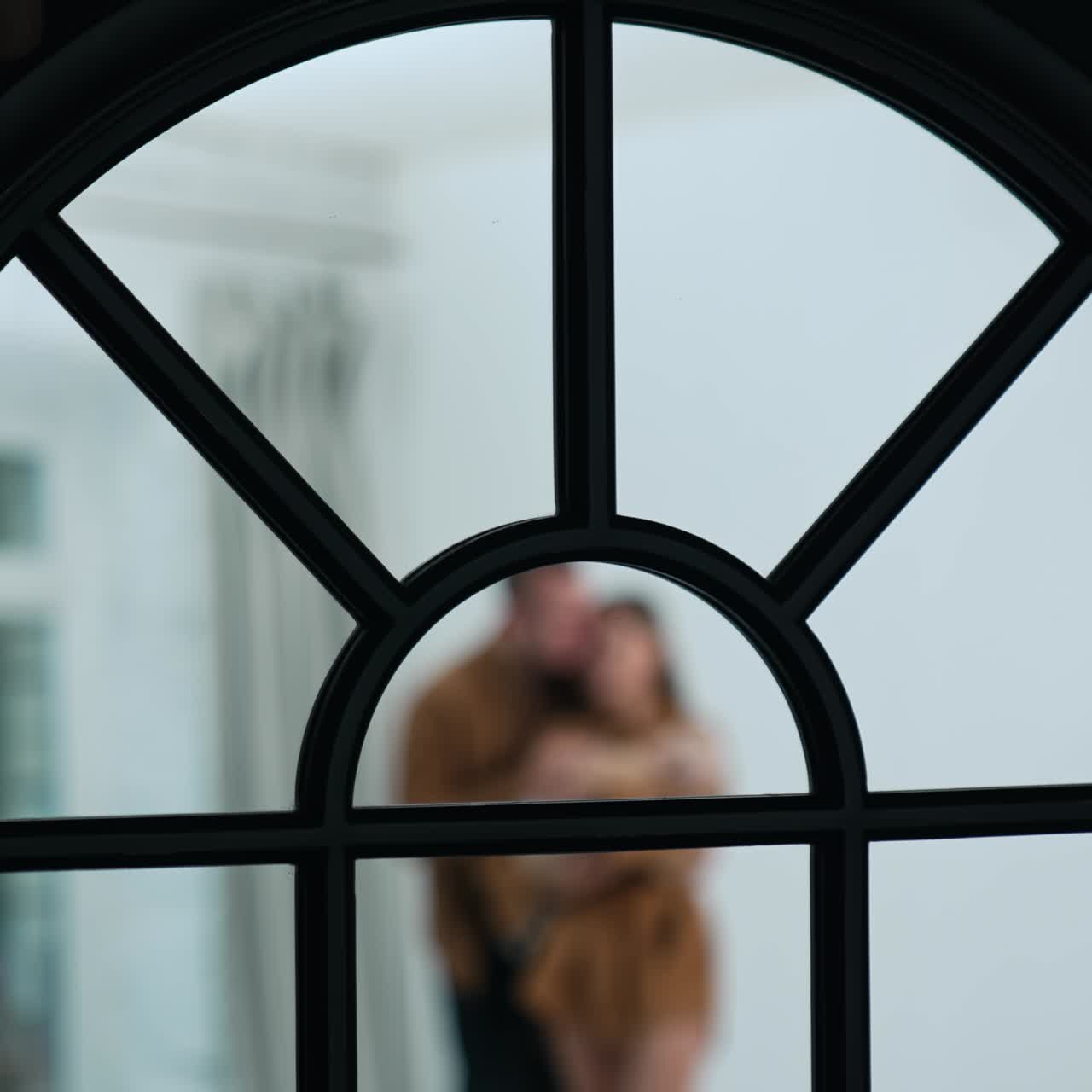 Parte superiore ad arco della finestra. Primo piano. Silhouette sfocata di una coppia sullo sfondo