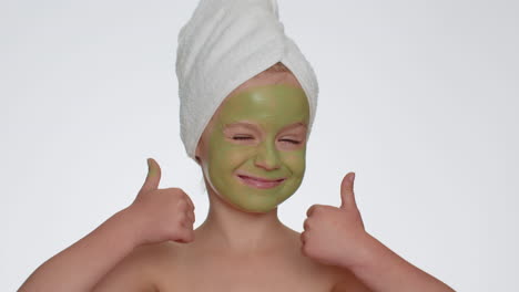 Beautiful-smiling-child-girl-kid-in-towel-on-head-applying-cleansing-moisturizing-green-mask-on-face