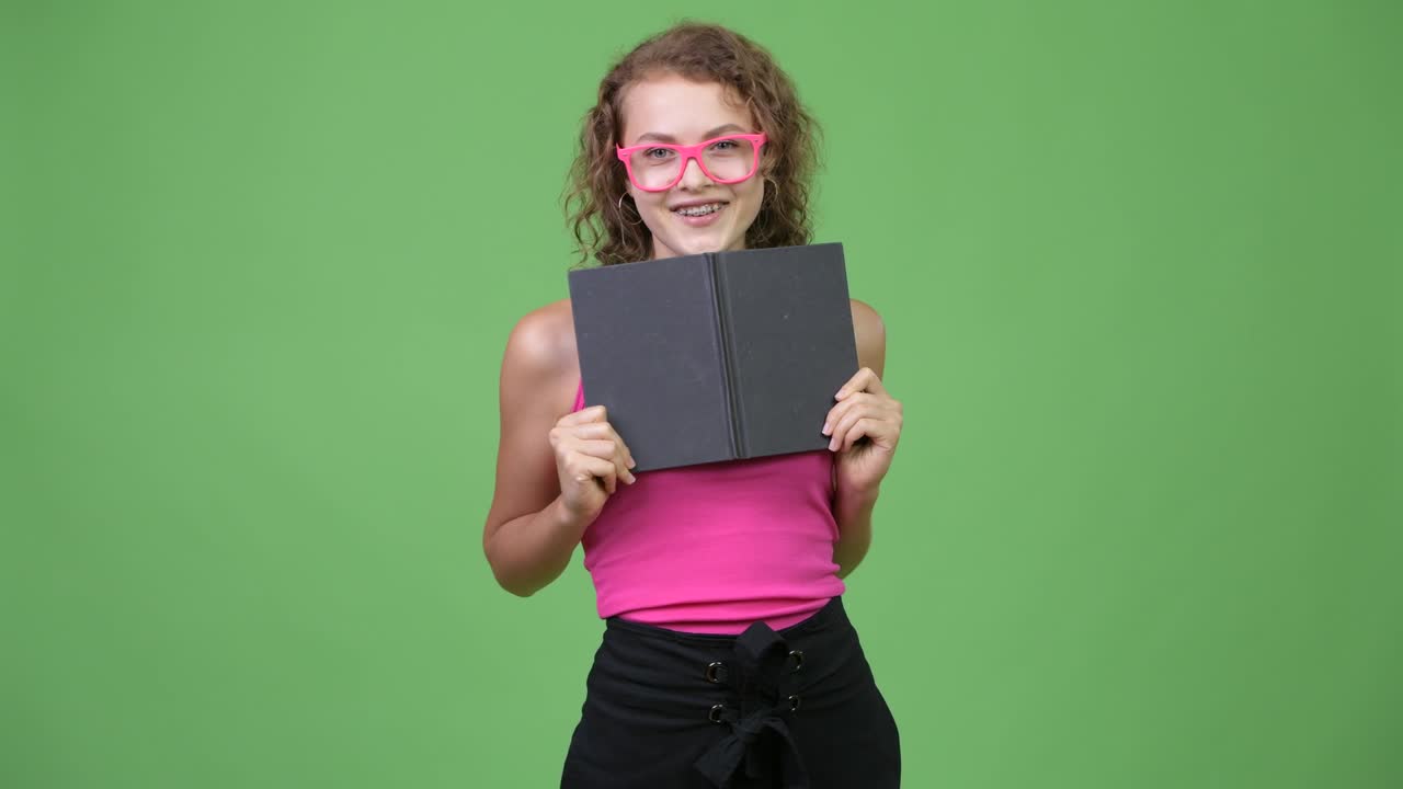 joven feliz tímida mujer nerd cubriendo la cara con un libro