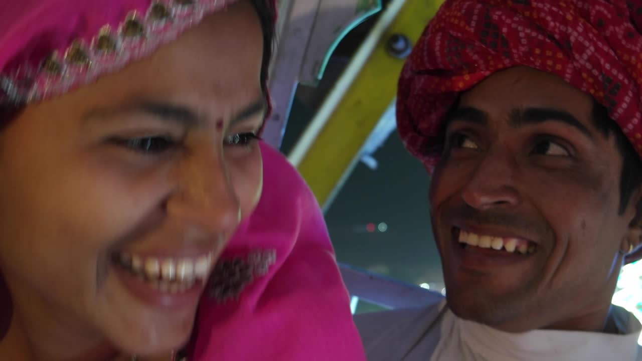 Indian couple enjoying ferris wheel ride in traditional dresses at the Pushkar Mela, a carnival of Rajasthan, India