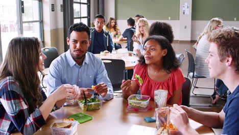 maestro y estudiantes almorzando en la cafetería de la escuela secundaria durante el recreo