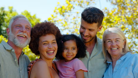 portrait of multi-generation family standing in garden smiling at camera