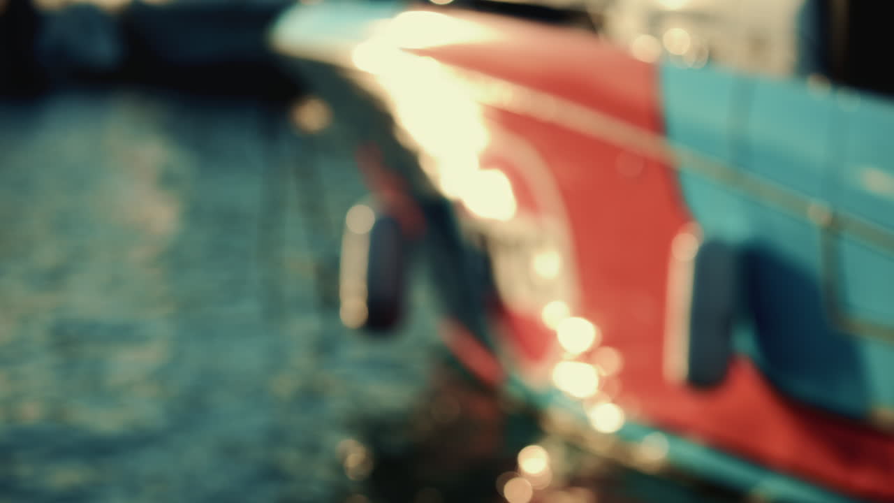 Nahaufnahme von farbenfrohen Spiegelungen eines Bootsrumpfes, die über die Wasseroberfläche kräuseln