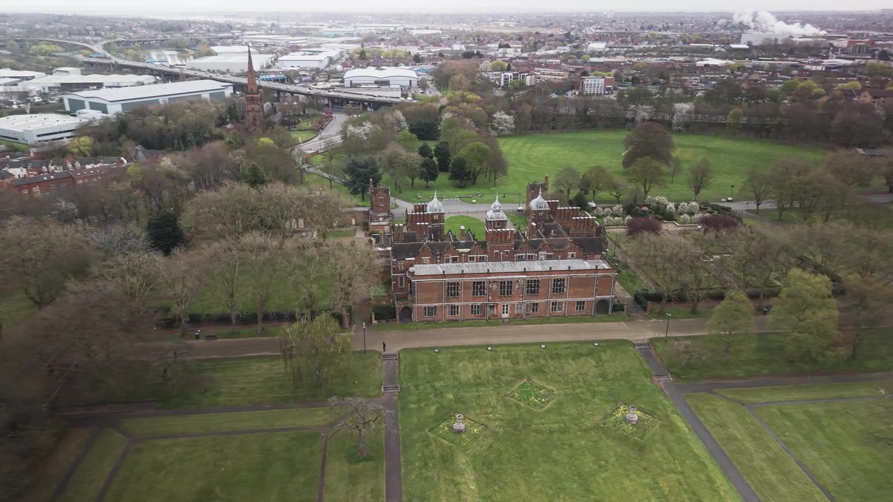 Vista aerea di Aston Hall a Birmingham con prati, alberi e lo skyline della città sullo sfondo.