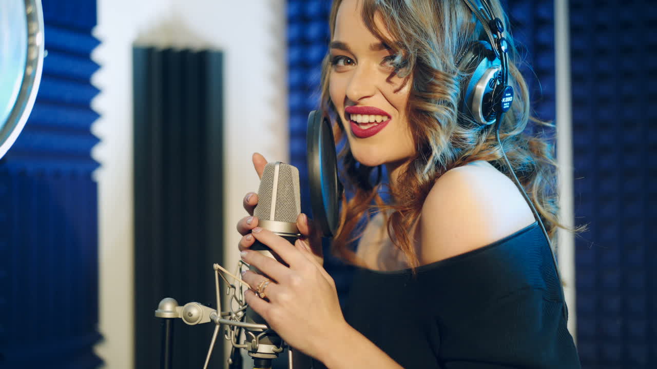 Vinnitsa, Ukraine - May 2019: Young woman recording a song in a professional studio. The girl sings into the microphone.