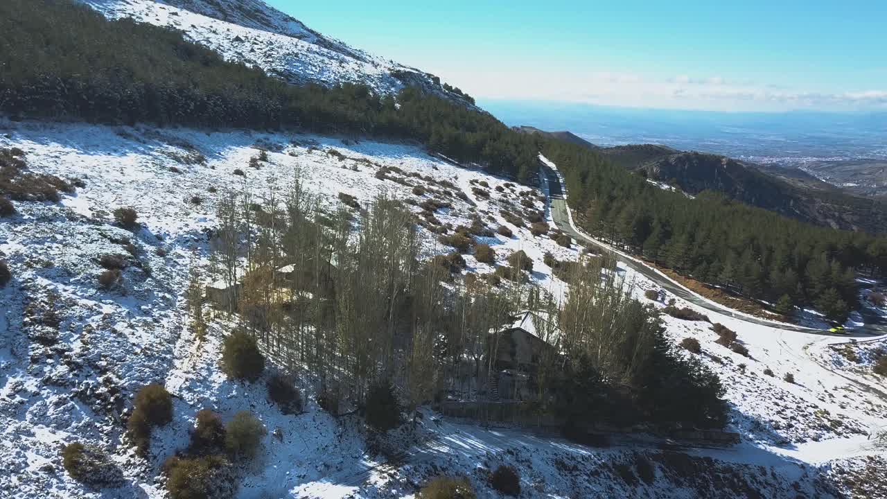 vista aérea de una carretera en montañas nevadas con un coche