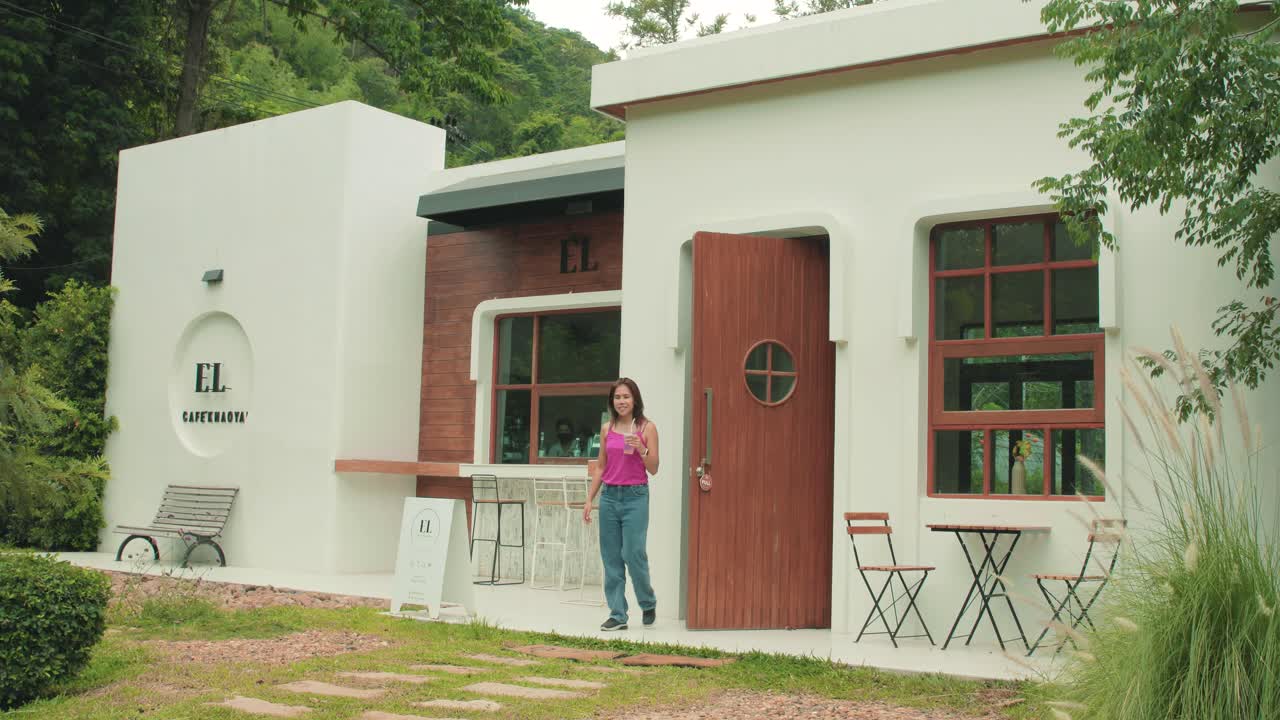 Beautiful Thai Woman Exiting a Modern and Contemporary Garden Caf&eacute; in Thailand