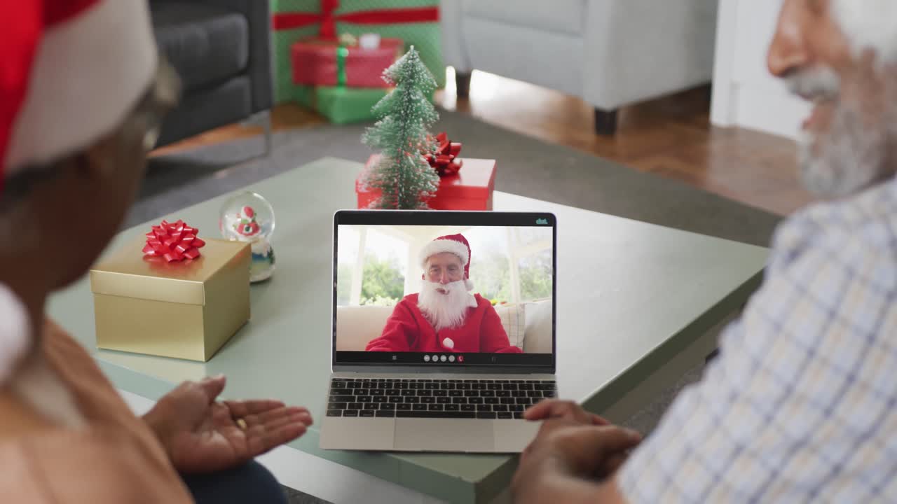 feliz pareja afroamericana de alto nivel en videollamada con santa claus en el tiempo de navidad