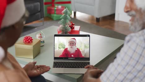 Happy-senior-african-american-couple-on-video-call-with-santa-claus-at-christmas-time