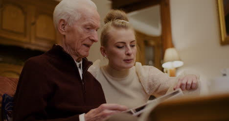 granddaughter looking at photo album with grandfather