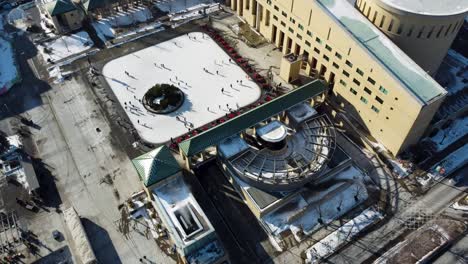 drone flying over mississauga town hall with a skating rink on a snowy winter day