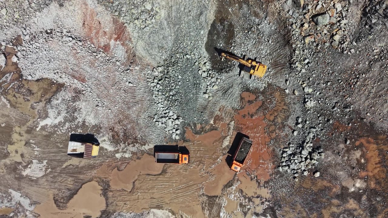 Granite quarry activity with trucks and machinery at work in large stone extraction area during daylight hours