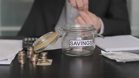 hombre de negocios poniendo dinero en vidrio con ahorros