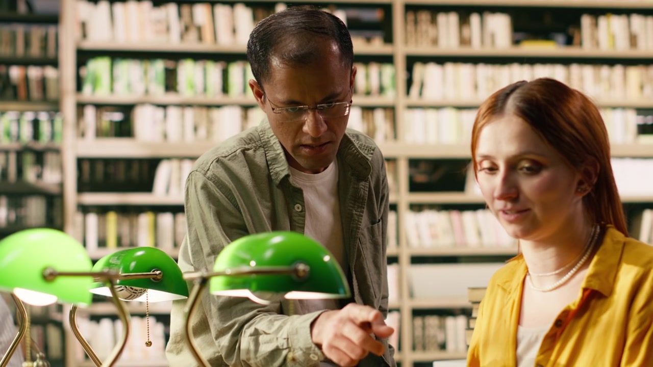 Tutor discussing study notes with woman student at library desk