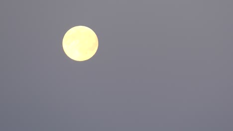 yellow moon moving across sky. time-lapse