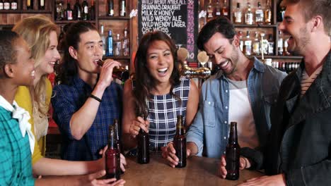 grupo de amigos sonrientes interactuando mientras tienen una botella de cerveza