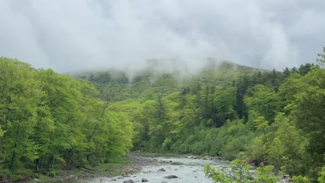 Panning-downward-on-a-stunning,-stormy,-foggy-day-in-the-Appalachian-Mountains-on-a-beautiful-river-during-summer