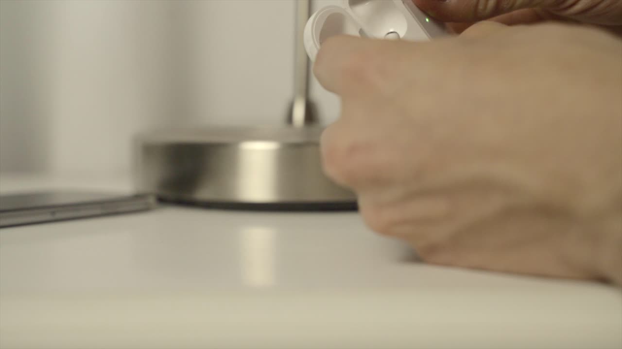 무선 블루투스 에어팟 이어폰을 집어드는 남자의 클로즈업 샷