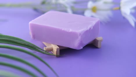 jabón de lavanda en un soporte de madera con flores y hojas