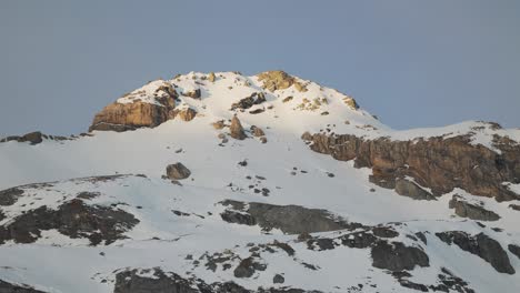 Aerial-view-showcasing-the-breathtaking-silhouette-of-snowy-mountain-range-at-sunrise,-captured-by-drone