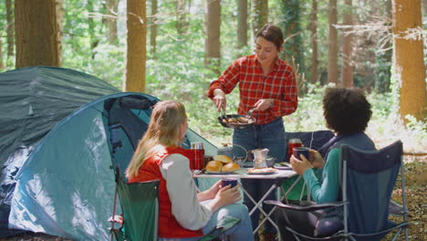 grupo de amigas en vacaciones de campamento en el bosque comiendo comida sentadas en una tienda juntos