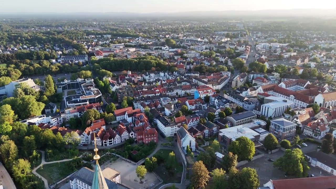 Droneoptagelse oppefra vipper fra katedralens skib og tårn i en bred kreds, der afslører klosteret, kapellet, biblioteket og byens skyline