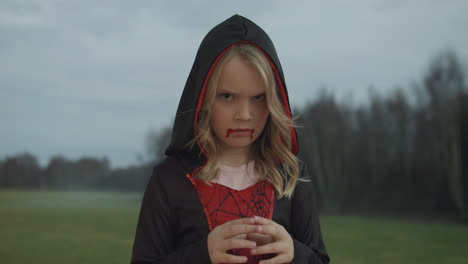 close-up medium video of girl in halloween dracula costume pulling faces and grimaces