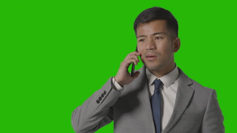 Studio-Shot-Of-Serious-Businessman-In-Suit-Taking-Call-On-Mobile-Phone-Against-Green-Screen-1