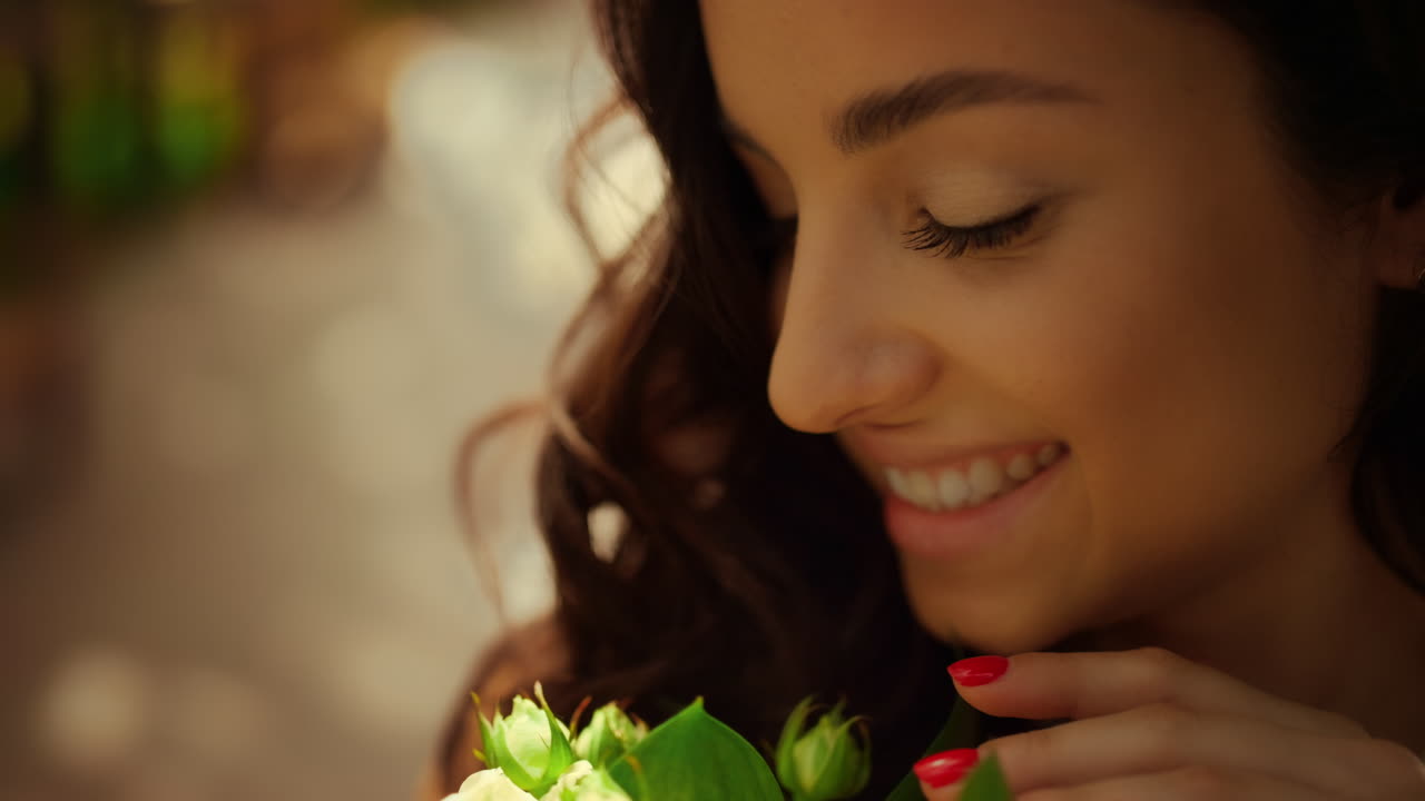 Mujer encantadora sonriendo en el parque. Novia alegre sosteniendo flores blancas en el jardín.
