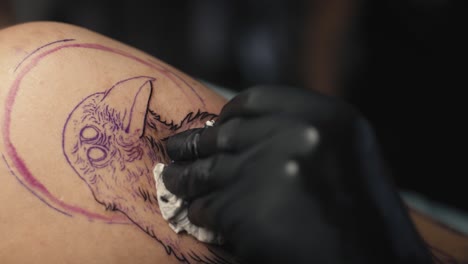 primer plano del artista del tatuaje dibujando en el brazo del cliente.