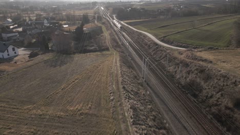 Vista-Aérea-Del-Tren-De-Pasajeros-En-Un-Día-Soleado-Durante-La-Hora-Dorada,-Junto-A-Campos-Agrícolas-Y-Pueblos---Concepto-De-Cómodo-Transporte-De-Pasajeros