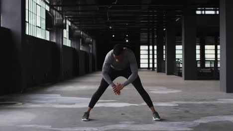 African-american-man-stretching-his-legs-in-an-empty-urban-building