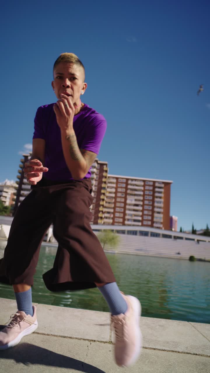 Energetic Woman Dancing and Jumping Outdoors by a City Lake