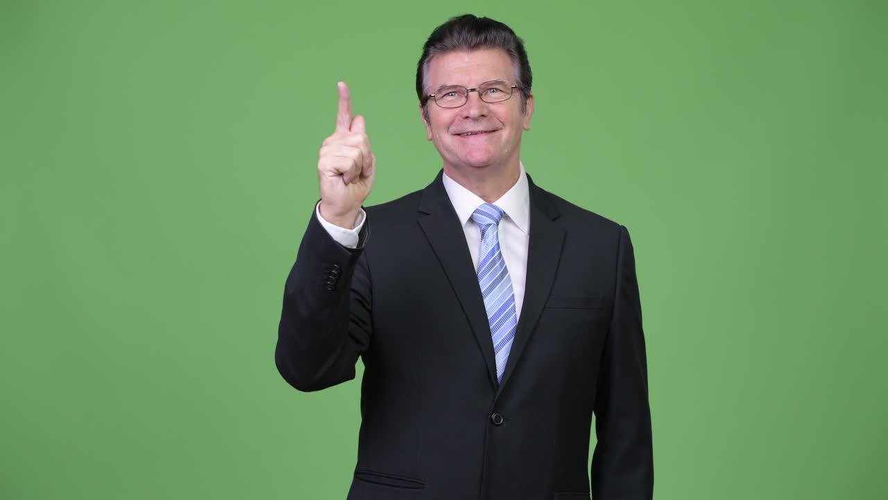 Senior handsome businessman thinking while pointing up