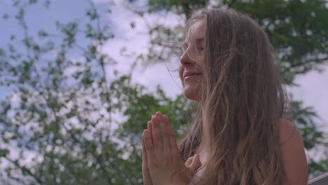 Young-Caucasian-woman-meditates-in-breeze-outside,-medium-shot