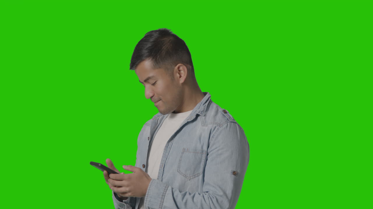 Studio Shot Of Casually Dressed Young Man Messaging On Mobile Phone Against Green Screen 2