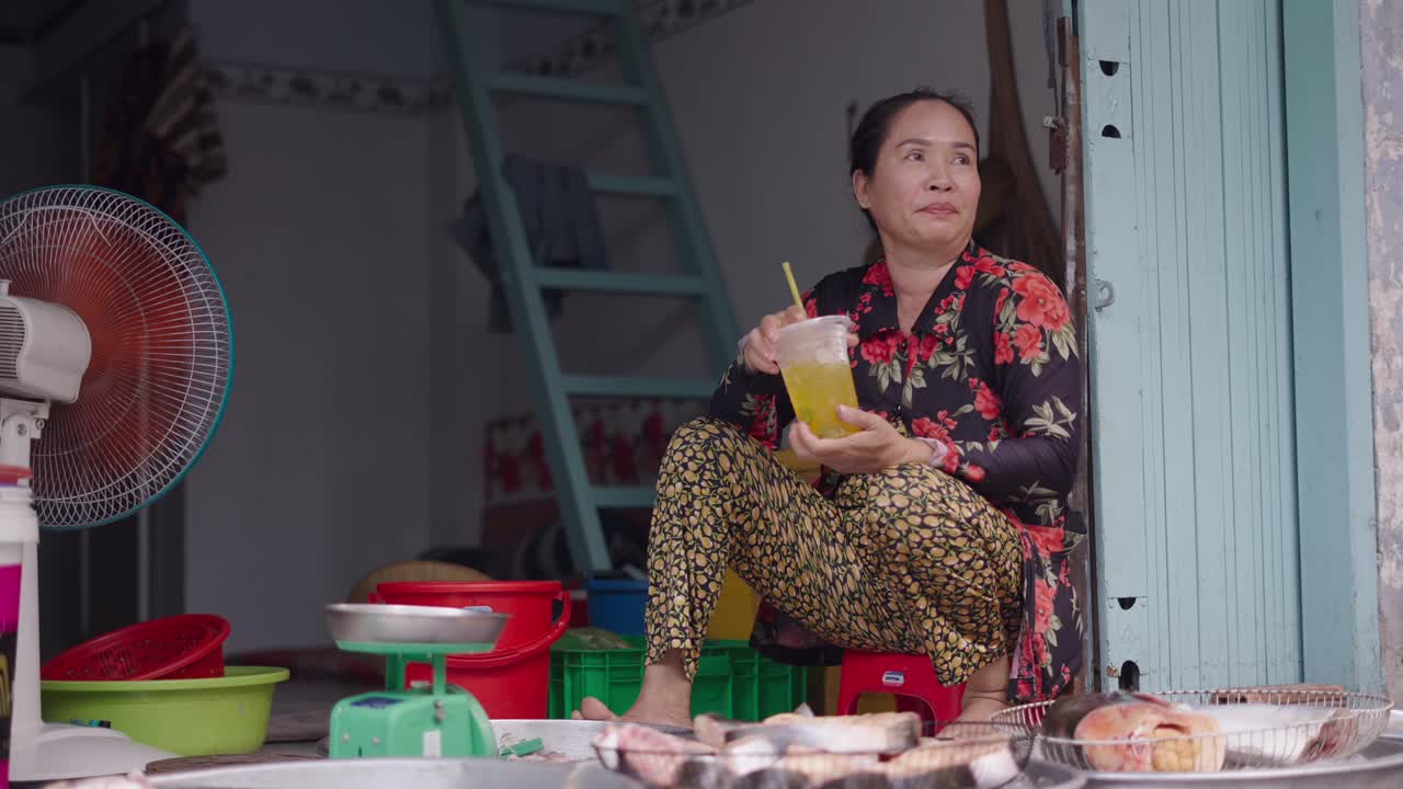 Woman Drinks Juice at a Fish Market