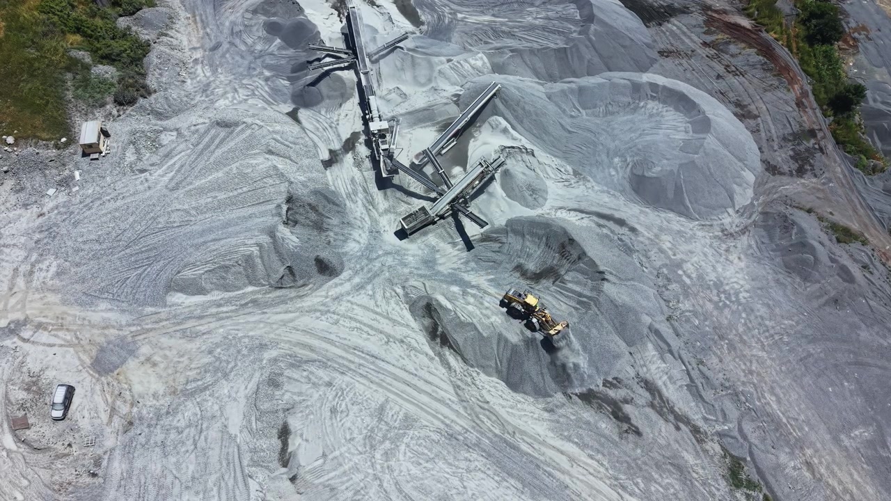 Granite quarry operation in a vast area uses machinery for stone extraction and processing at midday under clear skies