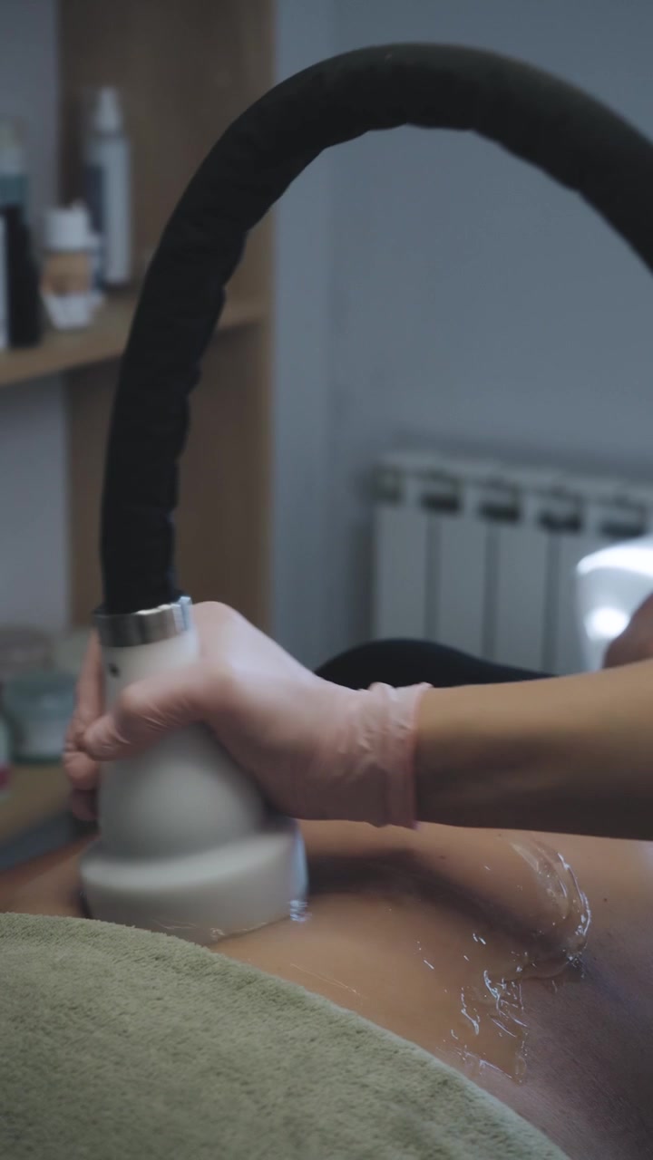 Professionista che esegue un trattamento di cavitazione per il rimodellamento del corpo su una cliente.