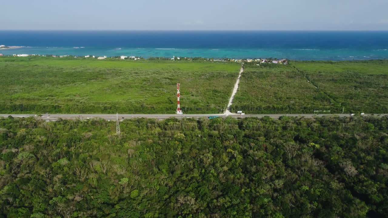 Aerial View of Tulum, Mexico; Undeveloped Land Near Highway and Radio Tower with Caribbean Sea in Background