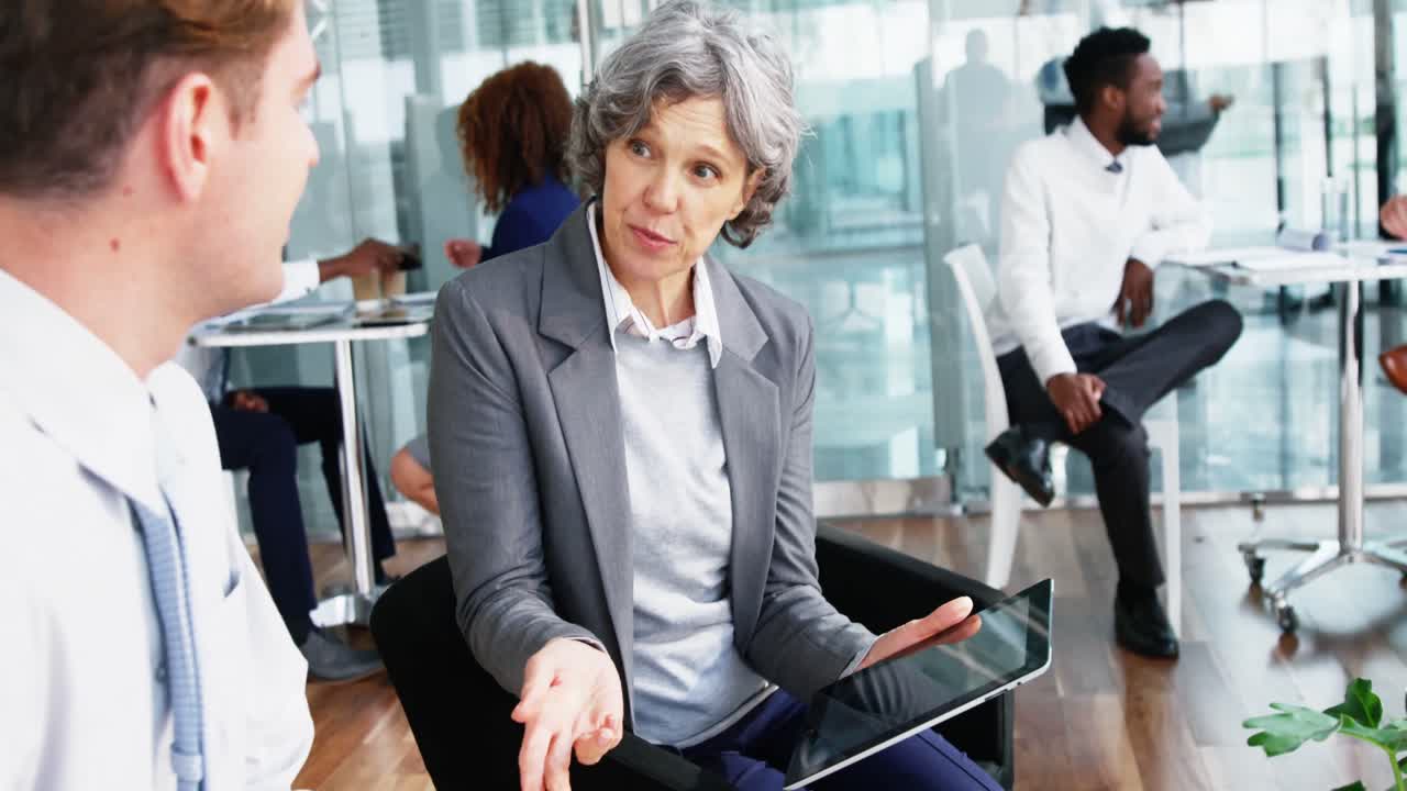 Empresária discutindo com um colega em um tablet digital