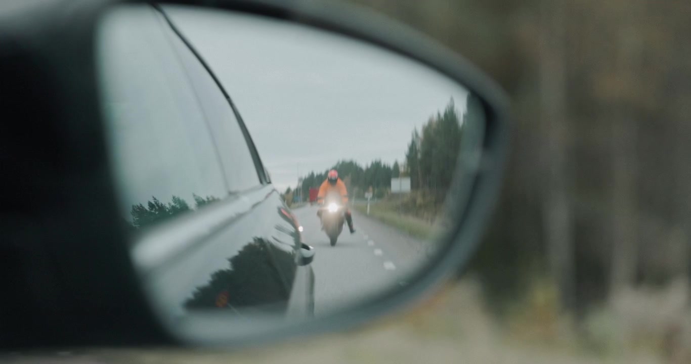 Un motociclista percorre le strade autunnali della Svezia, affrontando curve strette e piegando molto, circondato da un vibrante fogliame autunnale e strade panoramiche tortuose