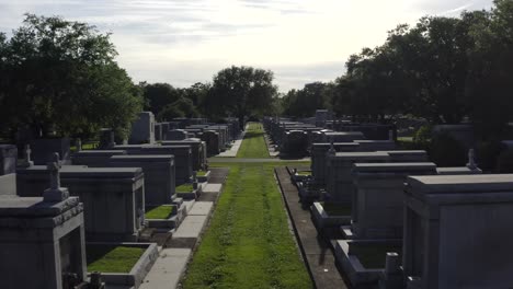 flying through mausoleums, statues and large head stones in a new orleans cemetery during sunset