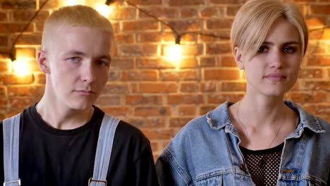 young cute couple of hipsters is dancing, moving necks, move conception, brick background, close-up