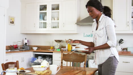 Mujer-Limpiando-La-Mesa-Del-Desayuno-Y-Cargando-El-Lavavajillas