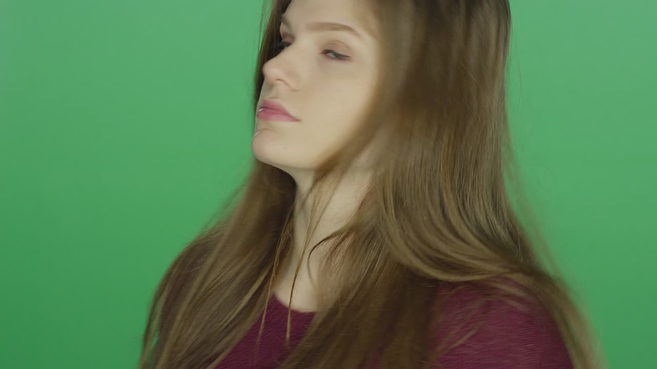 젊은 갈색 여성이 초록색 스크린 스튜디오 배경에 쳐다보고 있습니다.