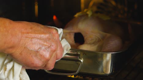 raw whole chicken with butter on top in deep tray going into oven to roast. fresh farmed food roasted. traditional centrepiece of sunday lunch dinner.