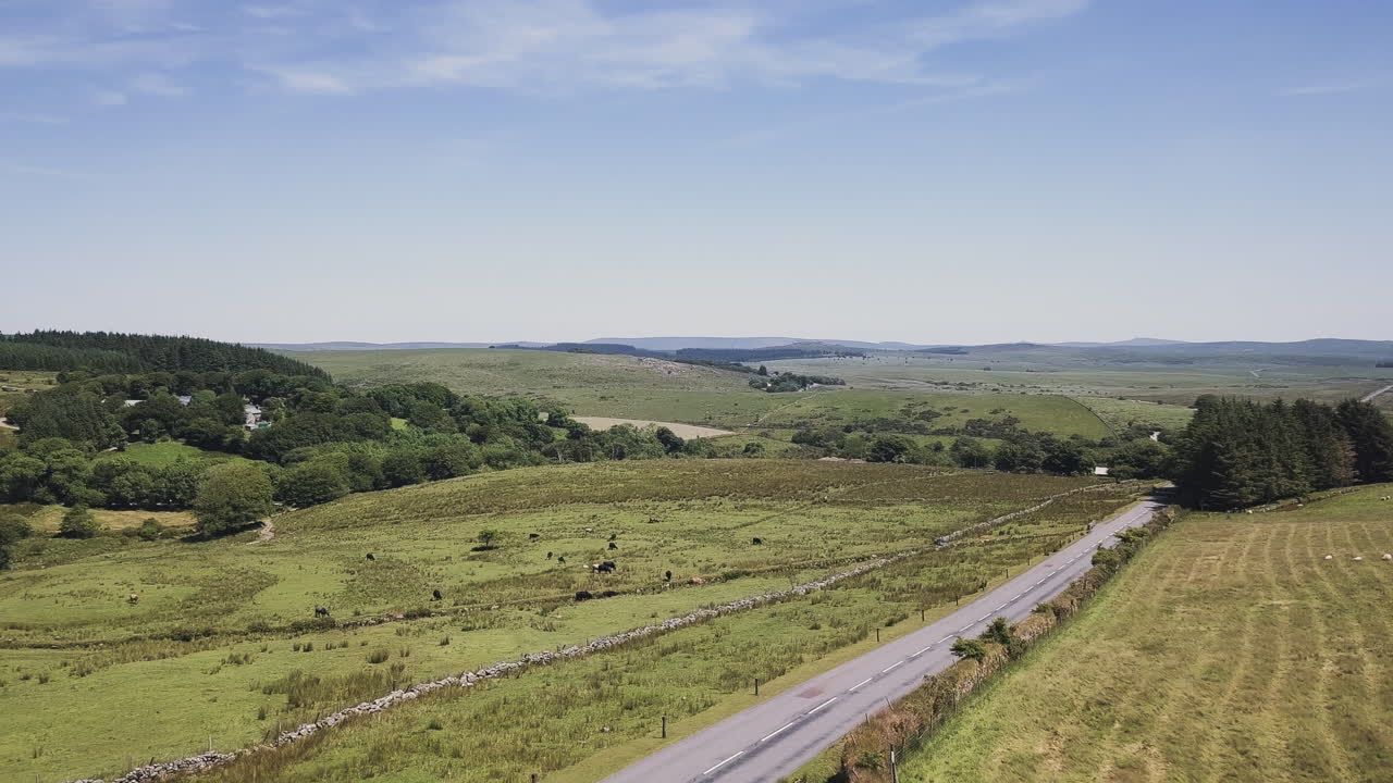 Aerial Zoom of a paved road through a rural landscape with rolling hills in Dartmoor, England